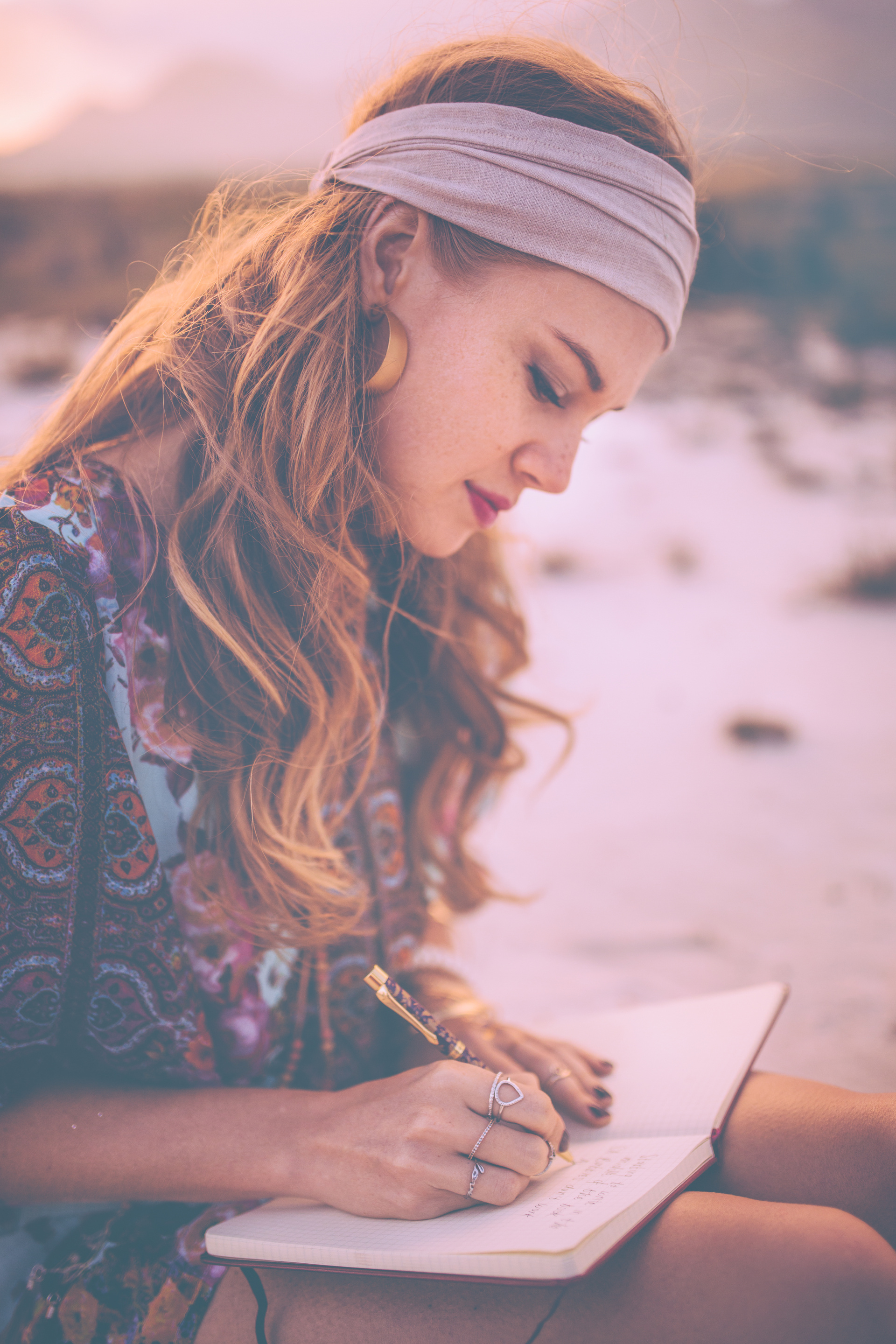 Boho girl writing in her journal while surronded by nature